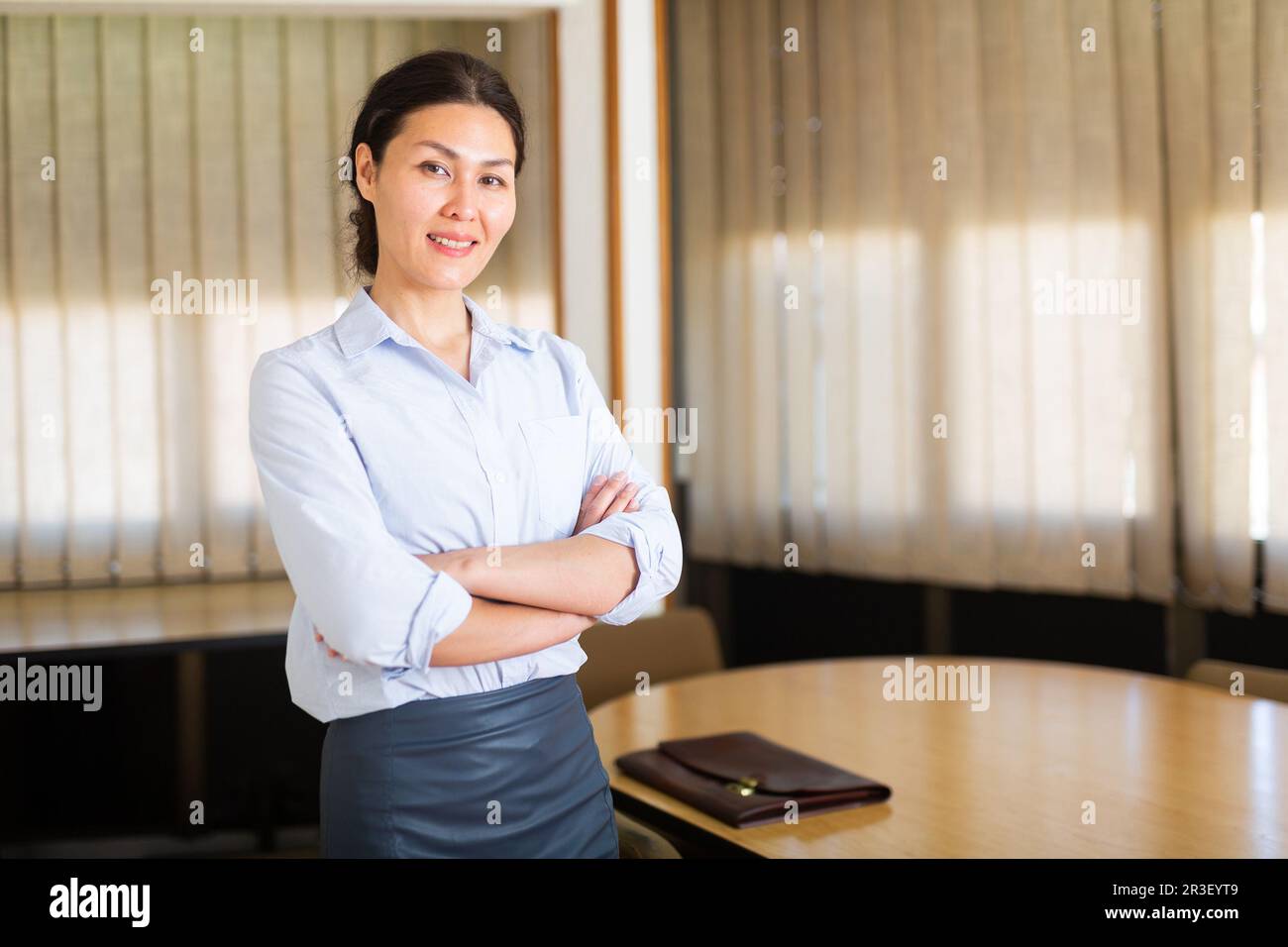 Successful business woman standing with arms crossed in office Stock ...