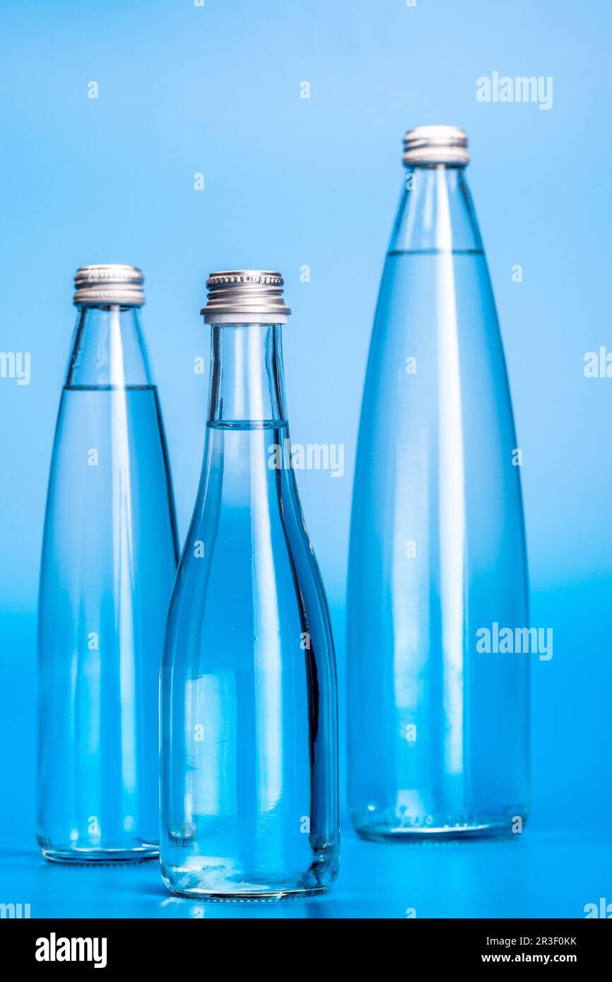 Glass water bottles on a light blue background Stock Photo - Alamy