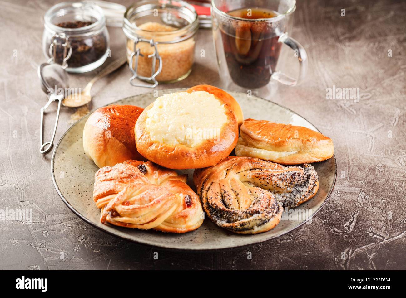 Sweet yeast dough pies with different fillings on platter and glass of ...