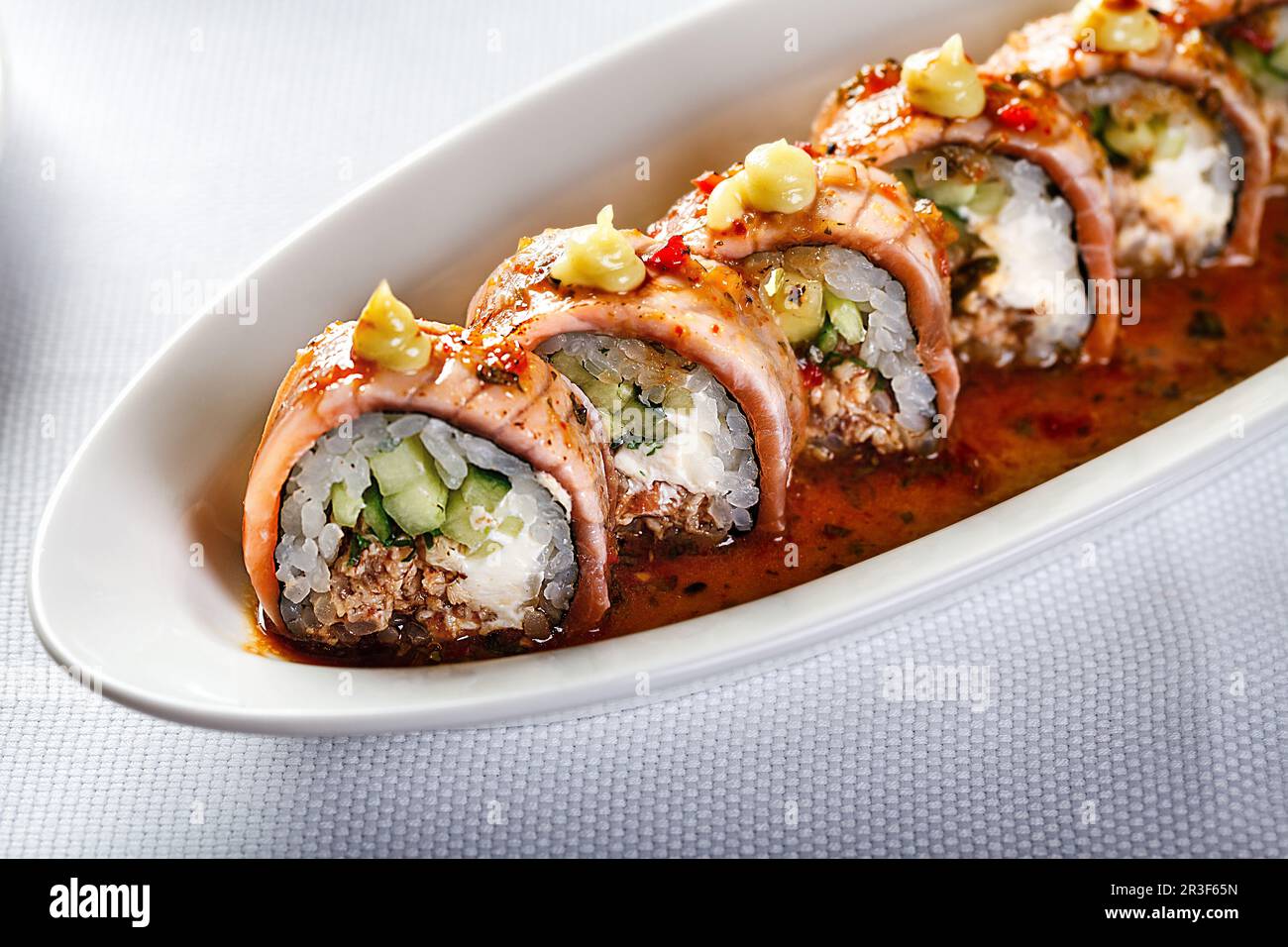Baked warm sushi rolls with eel, cucumber and smoked salmon Stock Photo