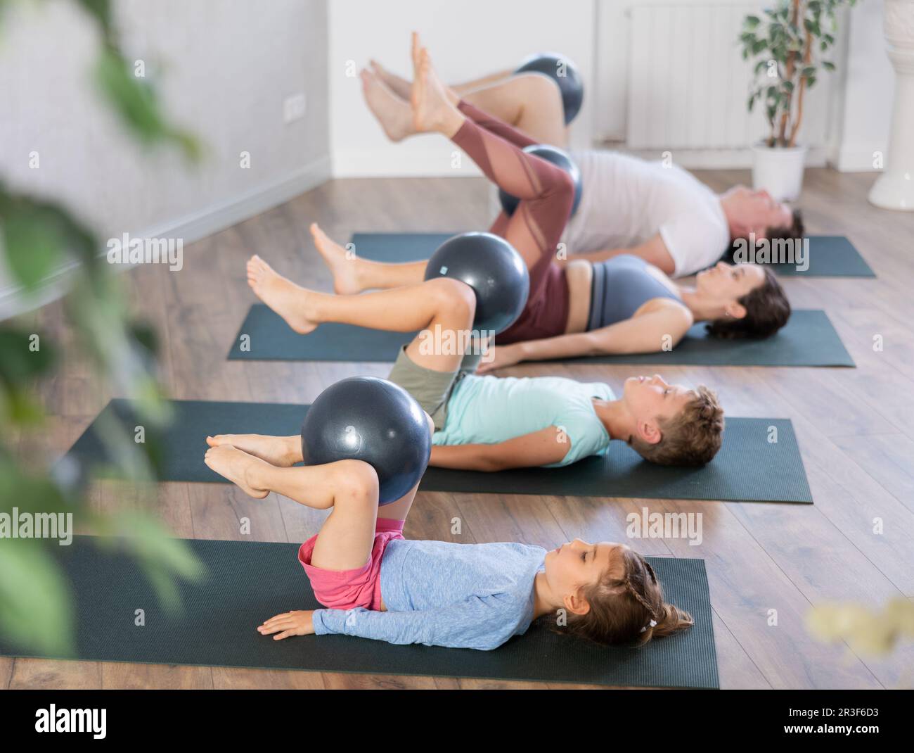 Mom, Dad and kids lying on backs on floor, lifting their knees bent at knees Stock Photo