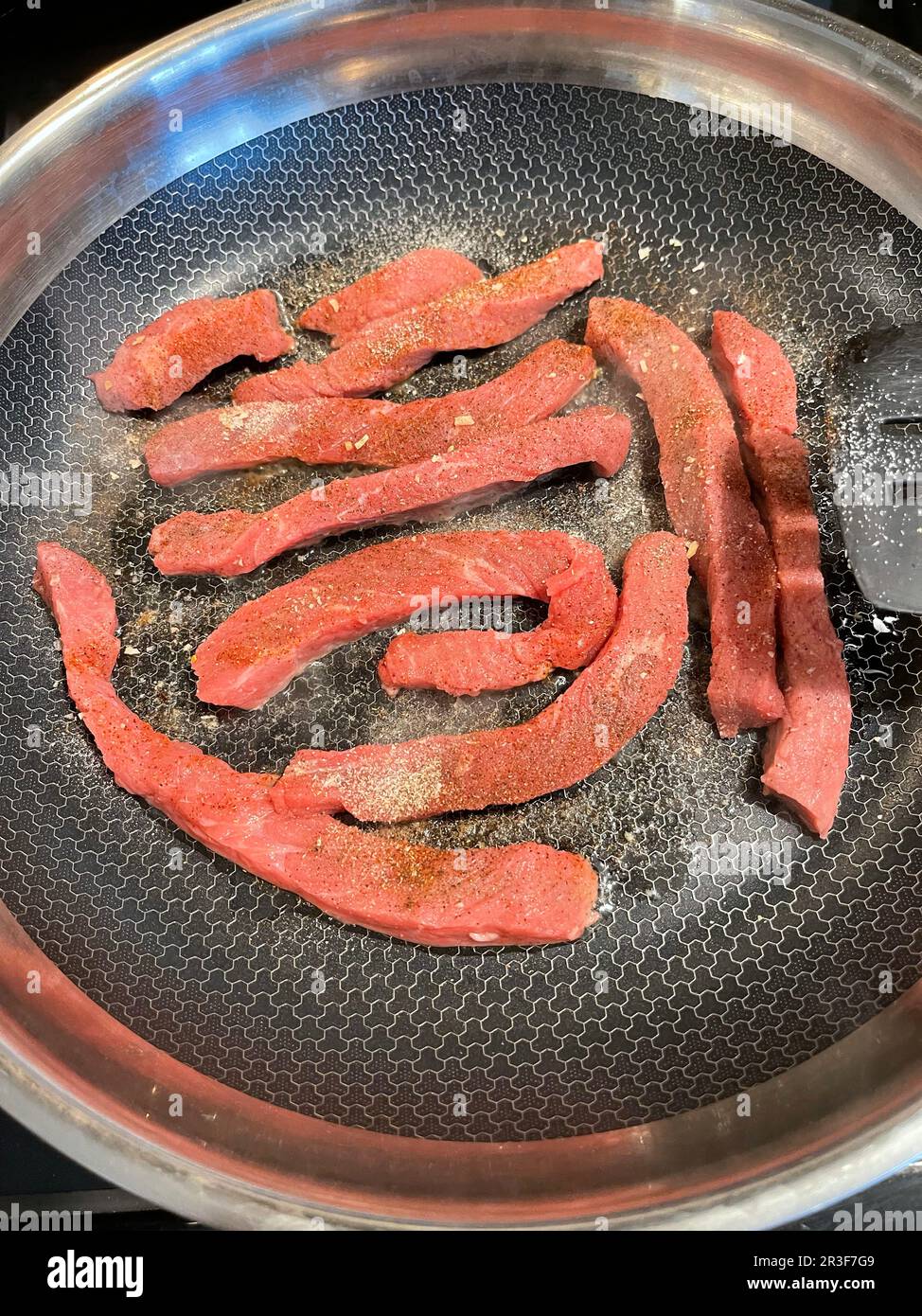 Fresh cut steak strips in a frying pan being slowly cooked Stock Photo