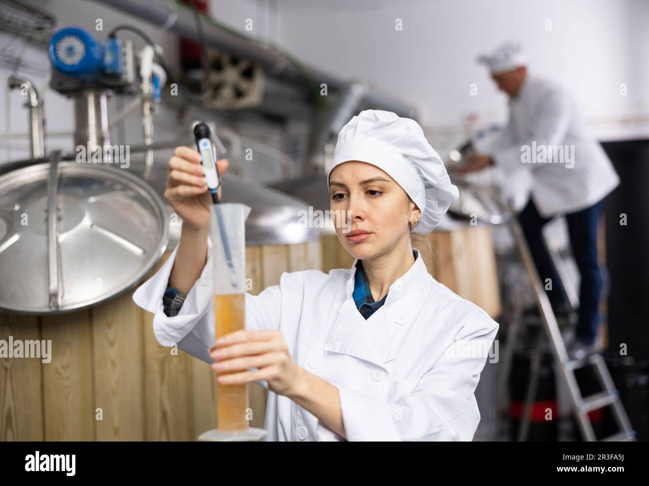 Female brewer using digital hydrometer for measuring beer density Stock
