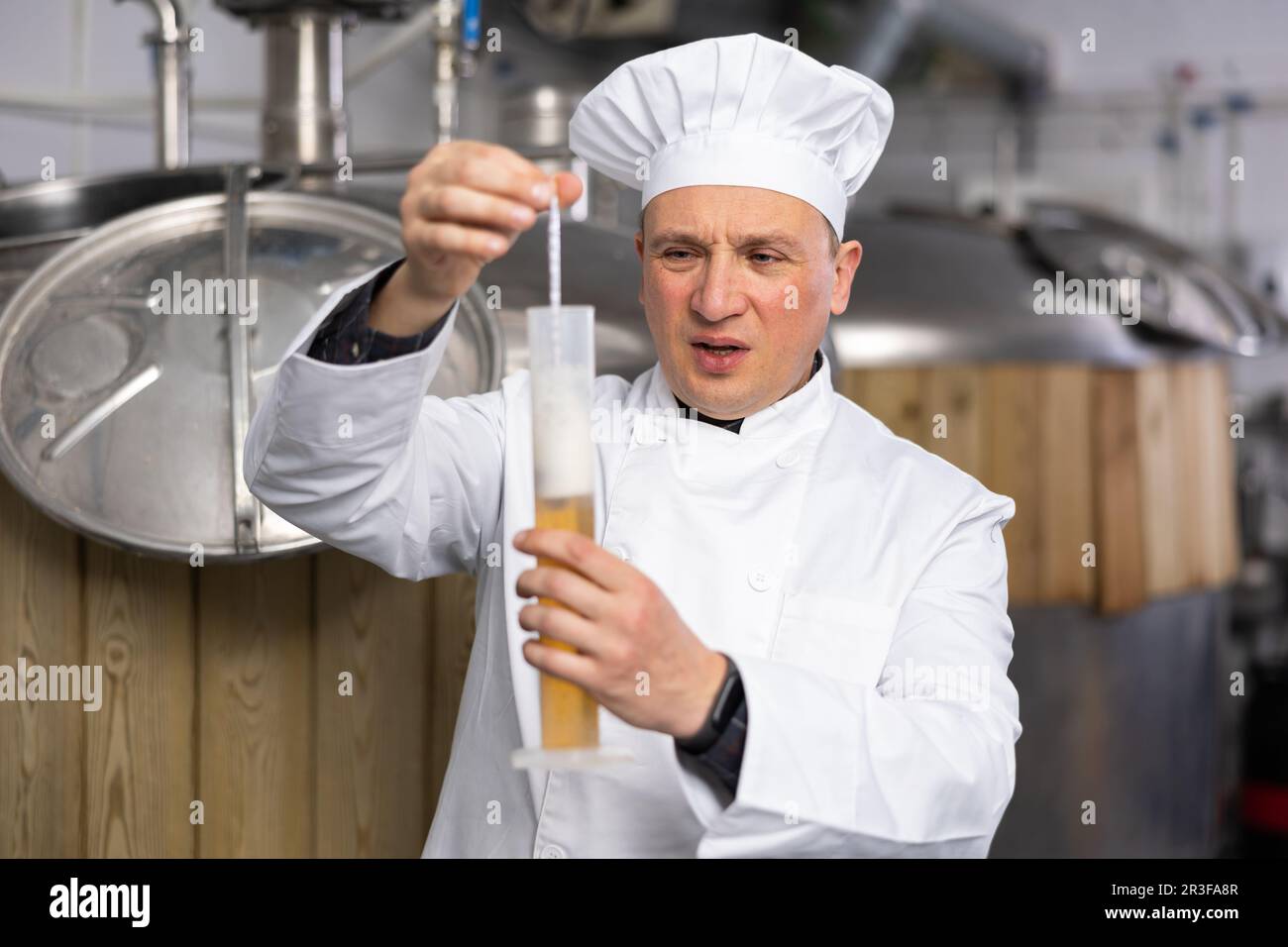 Frustrated man brewmaster measuring beer with alcoholometer Stock Photo
