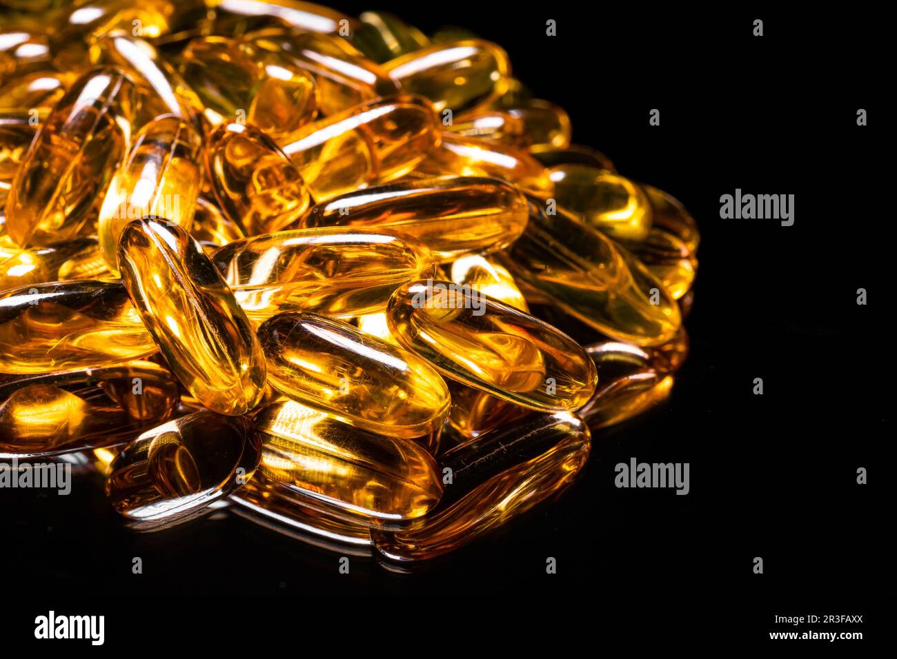 Close up of Omega 3 gel capsule on a reflective black background Stock