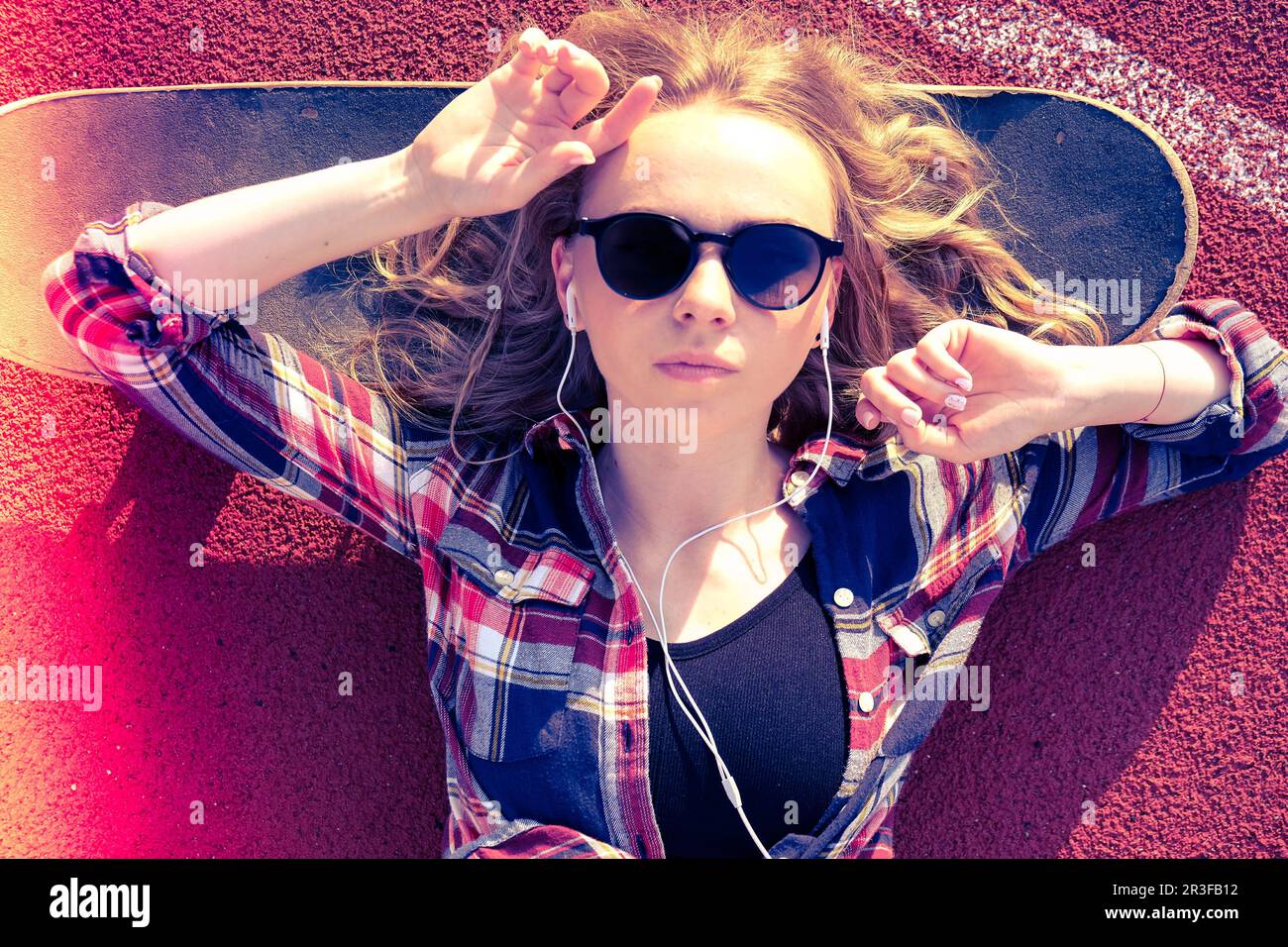 Millennial hippie Woman with sunglasses and headphones lying down on a