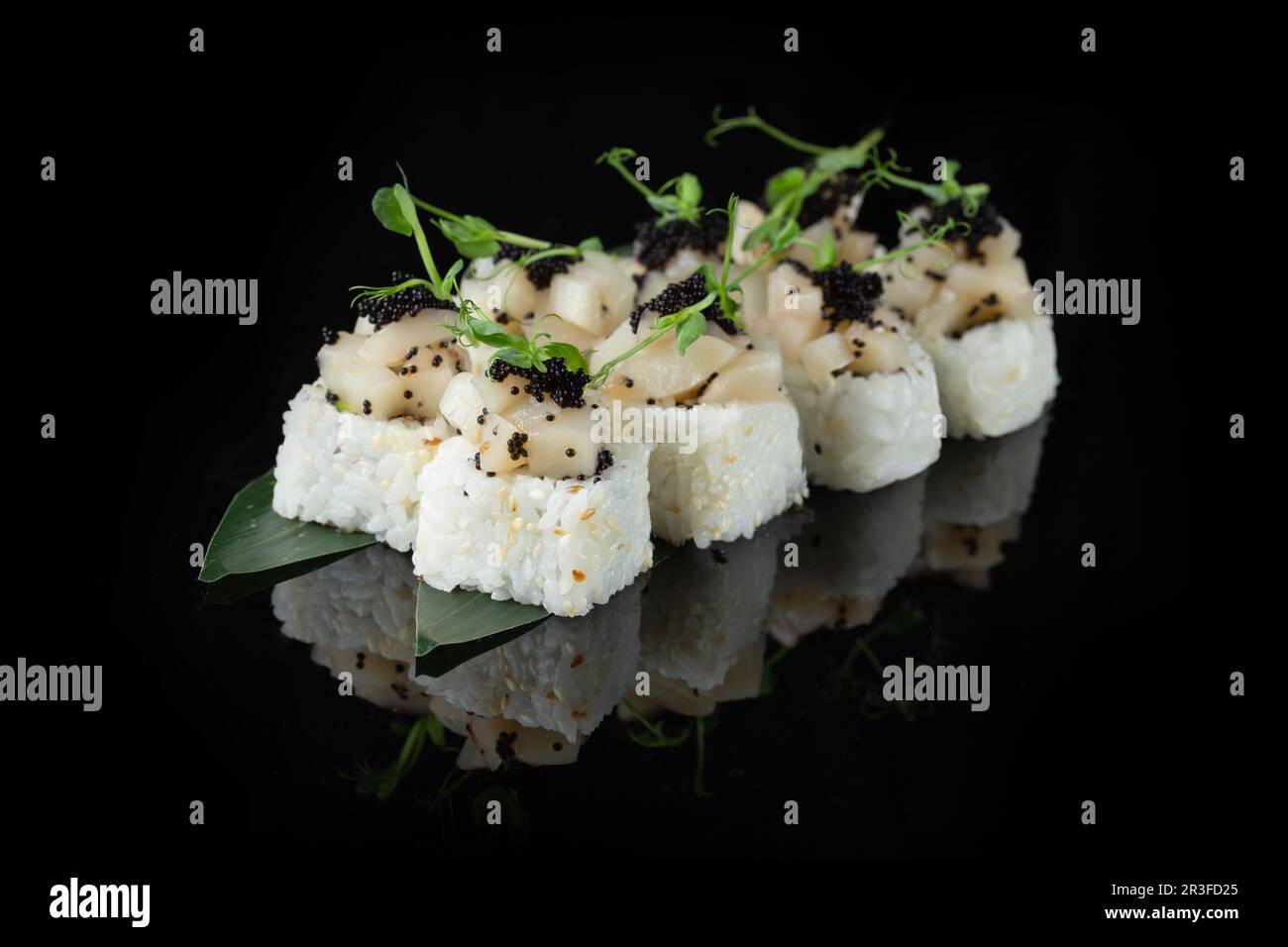 Traditional delicious fresh sushi roll set on a black background with reflection. Sushi roll with rice, nori, cream cheese, tobi Stock Photo