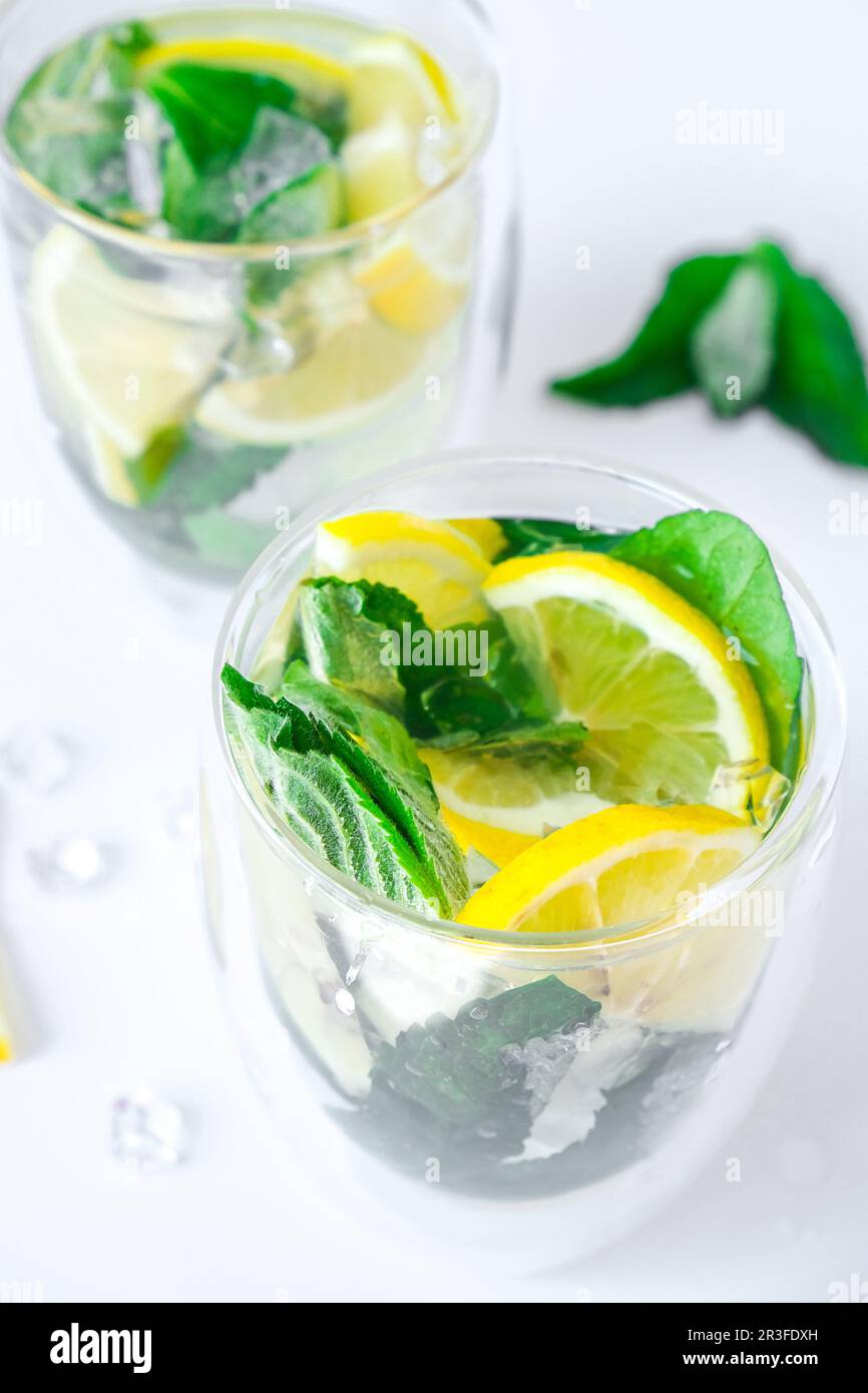 Mojito refreshing cocktail, alcohol drink. Lemonade with lemon and mint leaves on light background. Ice cubes. Summer refreshing Stock Photo