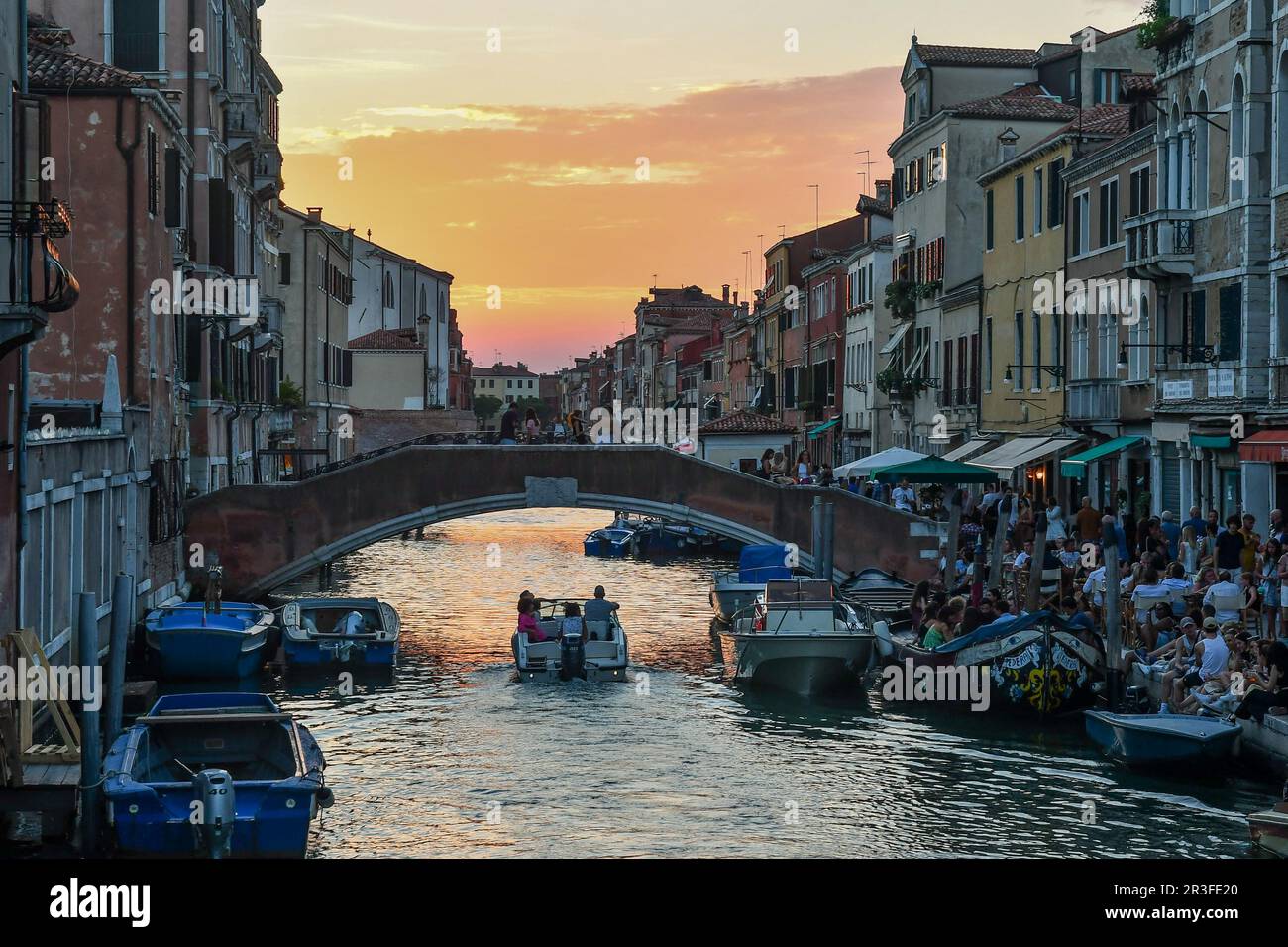 Bridge and Fondamenta dei Ormesini waterfront overlooking Rio della Misericordia canal, crowded with tourists on a summer evening at sunset, Venice Stock Photo