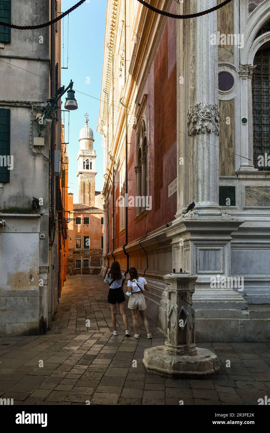 Calle (narrow alley) next to the Scuola Grande di San Rocco (right) with the bell tower of the church of San Pantalon in the background, Venice, Italy Stock Photo