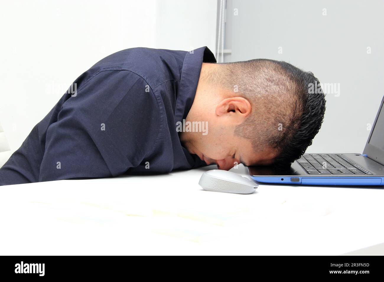 Dark-haired latin adult man works in his office with laptop with a lot of stress having a headache with a migraine and suffering from tiredness Stock Photo