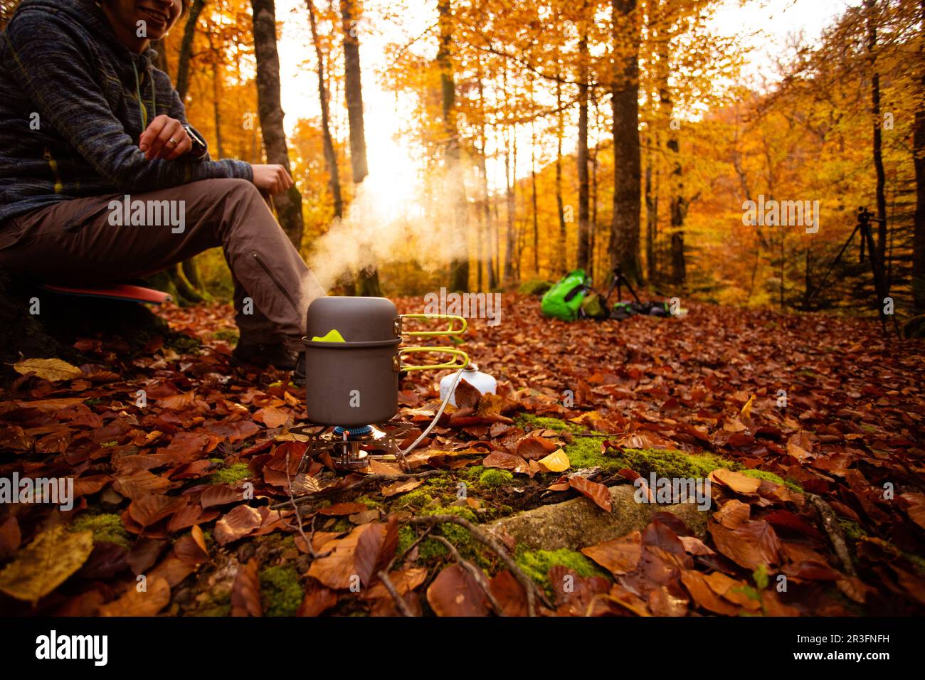 Woman uses portable gas heater and pan for cooking outdoors Stock Photo