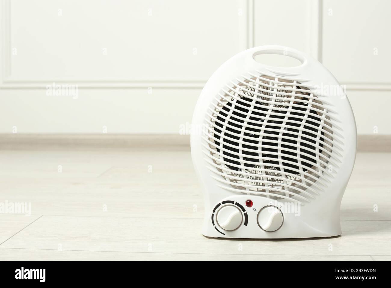 Modern electric fan heater on floor indoors, space for text Stock Photo