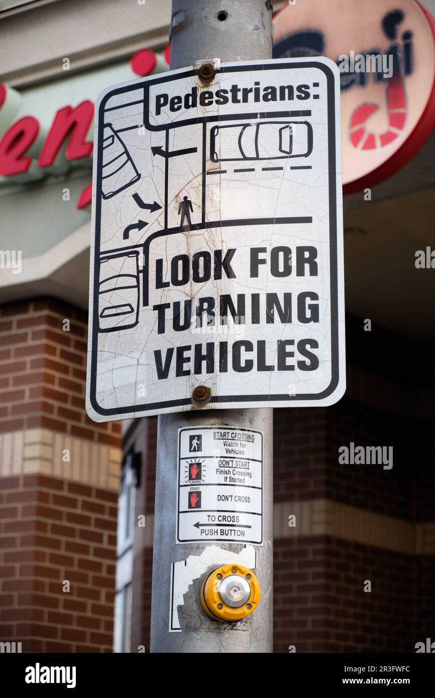 Pedestrians look for turning vehicles street sign Stock Photo