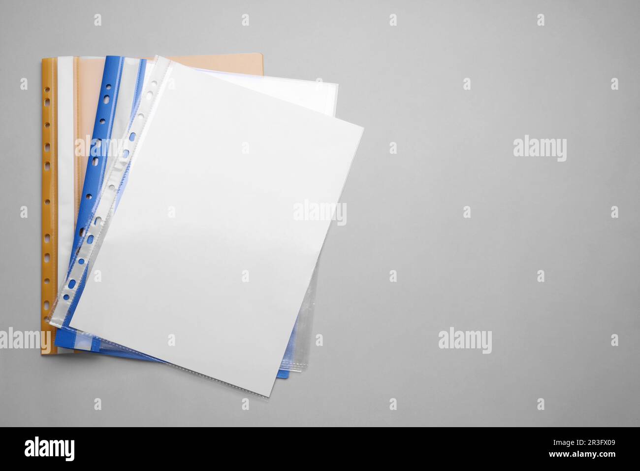 File folders with punched pockets and paper sheets on light grey
