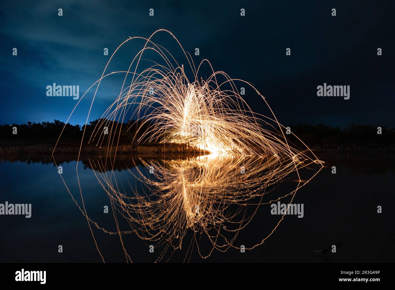 Beautiful figures and flashes of light painting reflected in a lake at night. Stock Photo