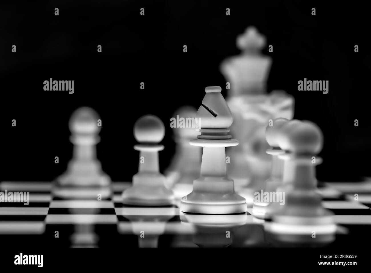 Close up of Chess pieces on a reflective mirror board surface with black background Stock Photo