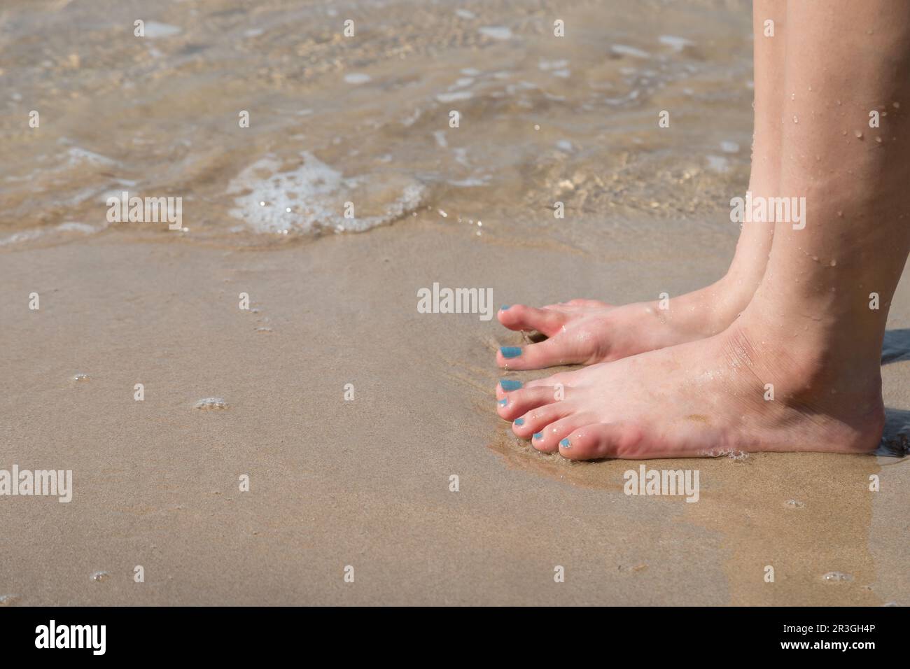 woman foot on the sand beach with sea water background Stock Photo