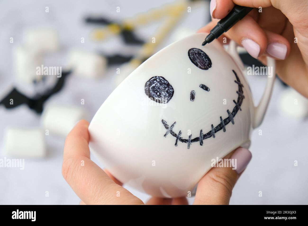 Female hands paint on white cup scary jacks face DIY for kids Halloween