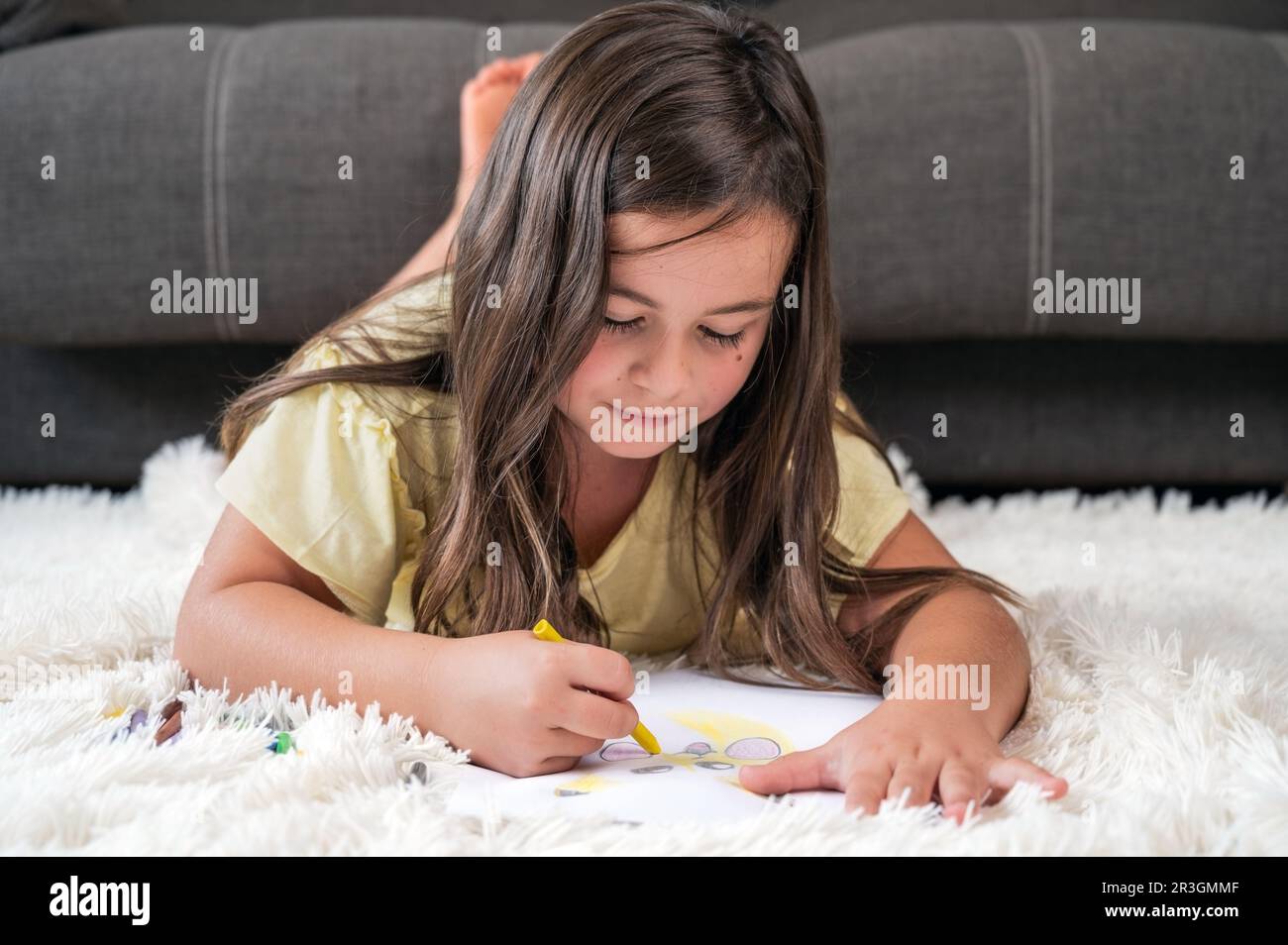 Cheerful little girl lying on the floor drawing Stock Photo - Alamy