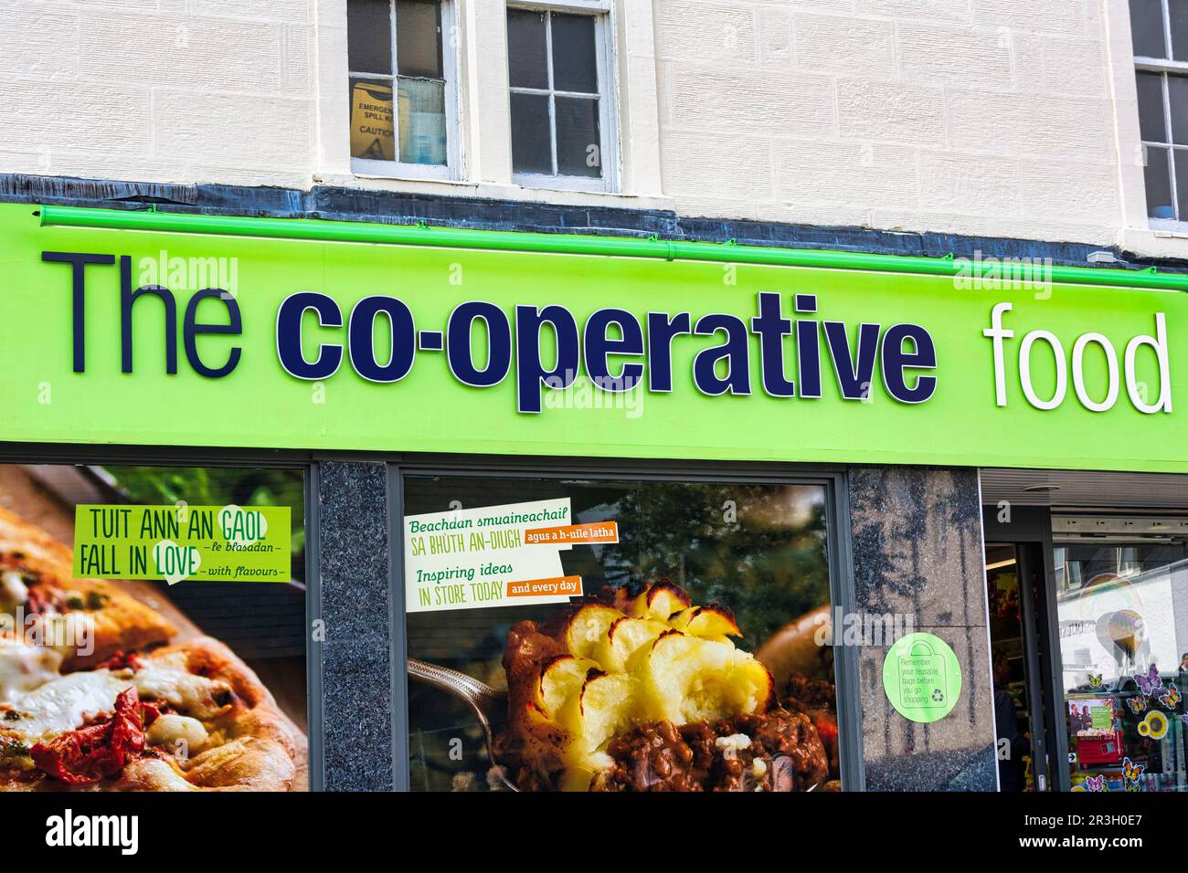 Supermarket, lettering food cooperative on facade, bilingual advertising posters in shop window, Portree, Isle of Skye, Inner Hebrides, Scotland Stock Photo