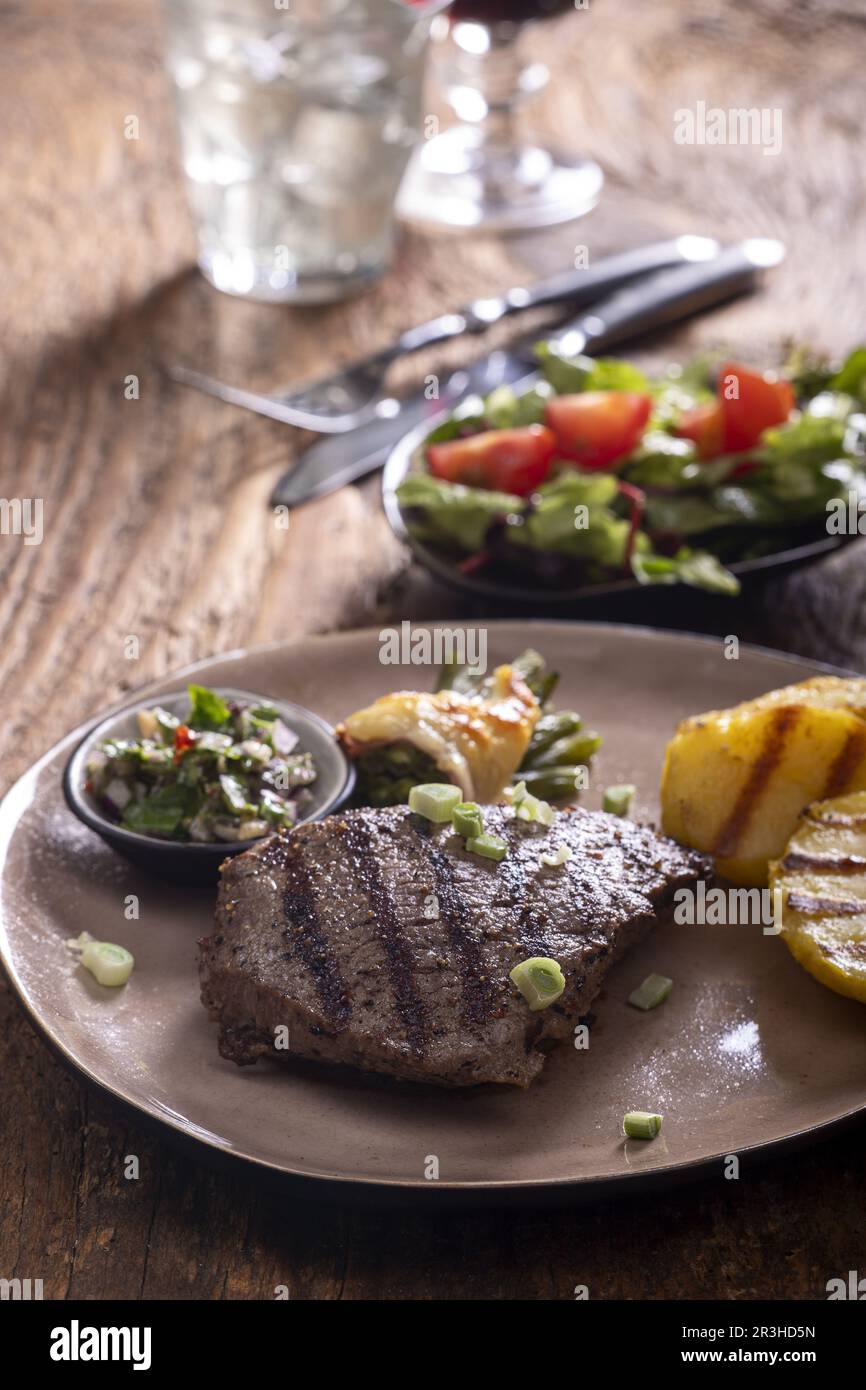 Grilled steak with chimichurri sauce on wood Stock Photo