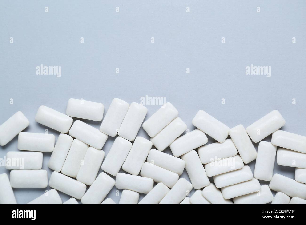 Tasty white chewing gums on light grey background, flat lay. Space for