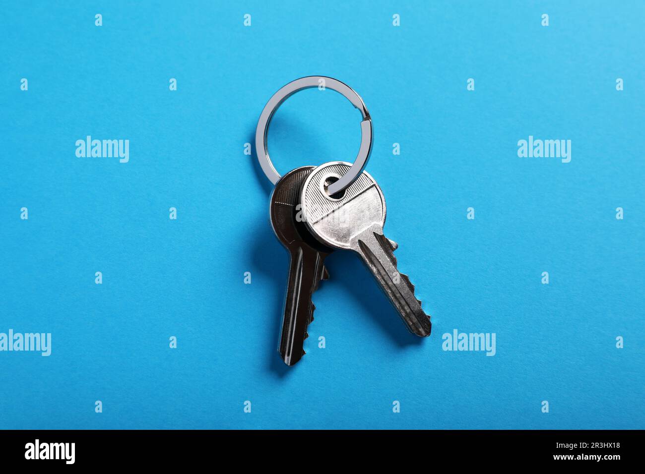 House keys on light blue background, top view. Real estate agent ...