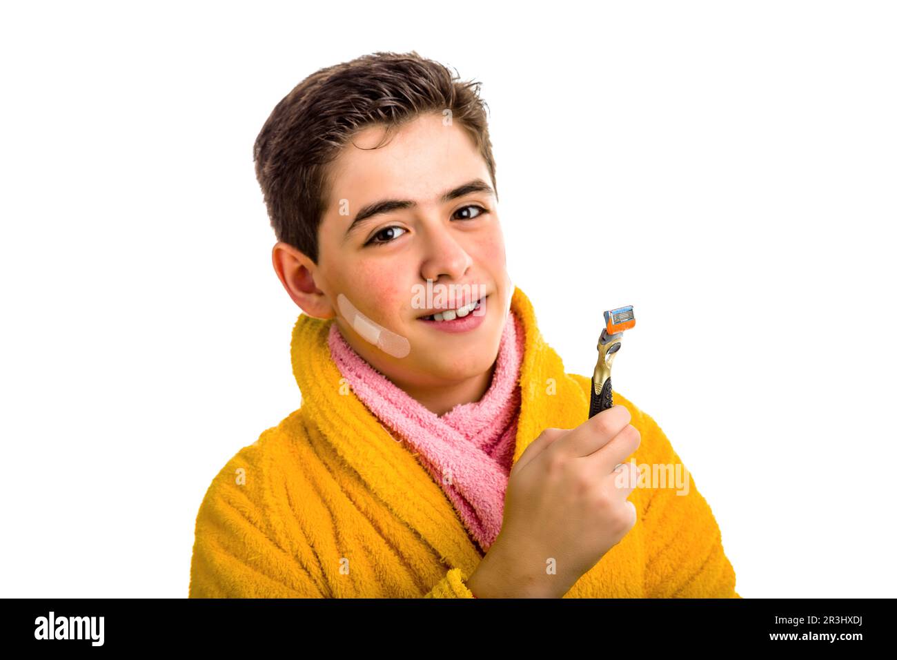 Boy in yellow bathrobe and pink towel smiles holding the razor used for ...