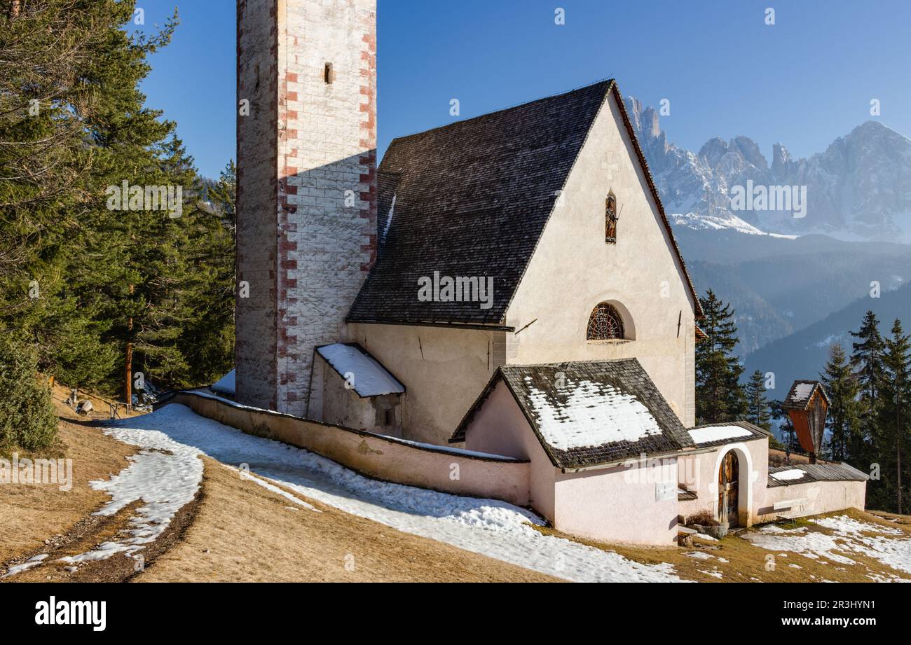 Church of St. Jacob overlooking pine forests and snow-capped peaks in winter Stock Photo