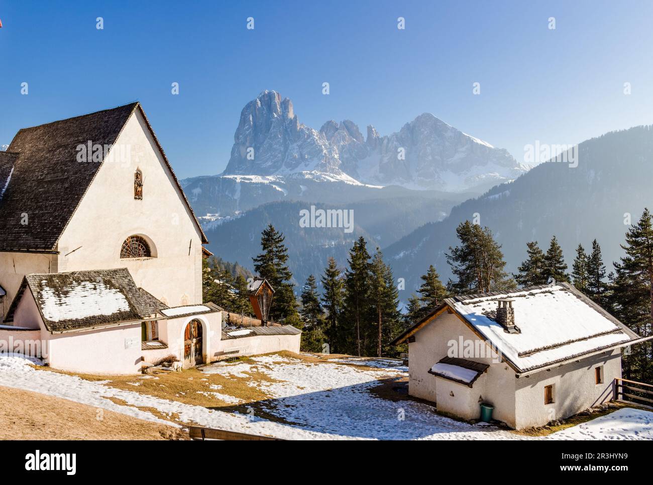 Church of St. Jacob overlooking pine forests and snow-capped peaks in winter Stock Photo