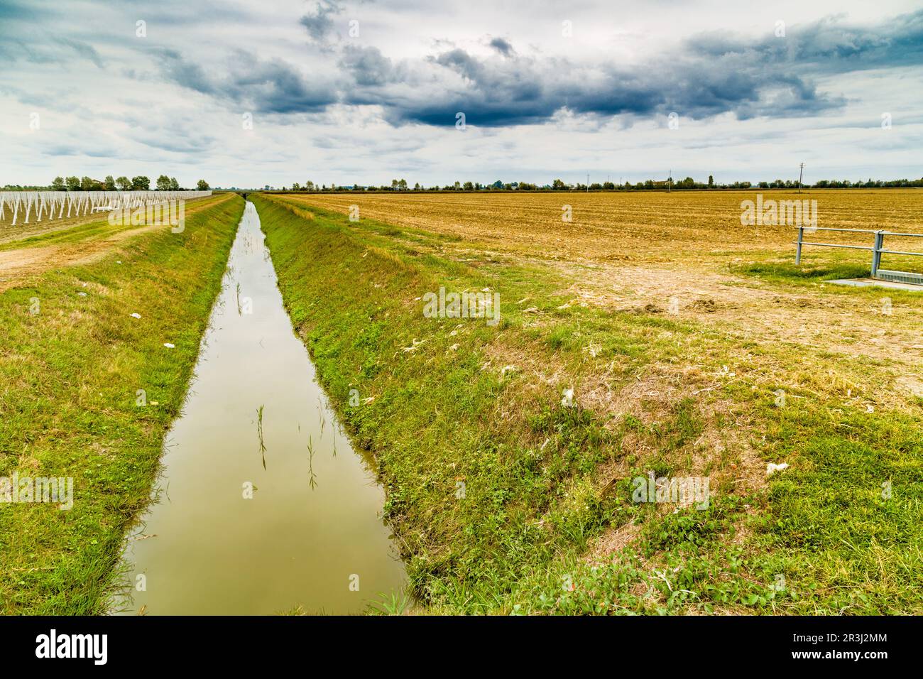 Irrigation canal divides harvested land and plowed land with precast
