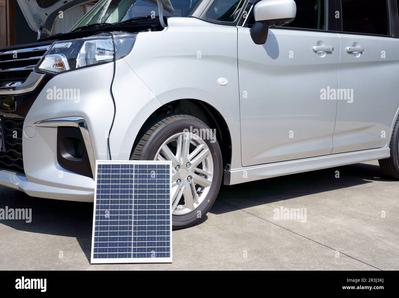 Portable solar photovoltaic panel, charging battery at car. Stock Photo