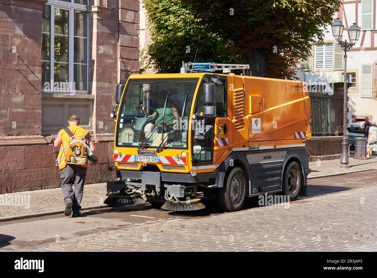 Worker cleaning the street with a sweeper in the old town of Colmar in France Stock Photo