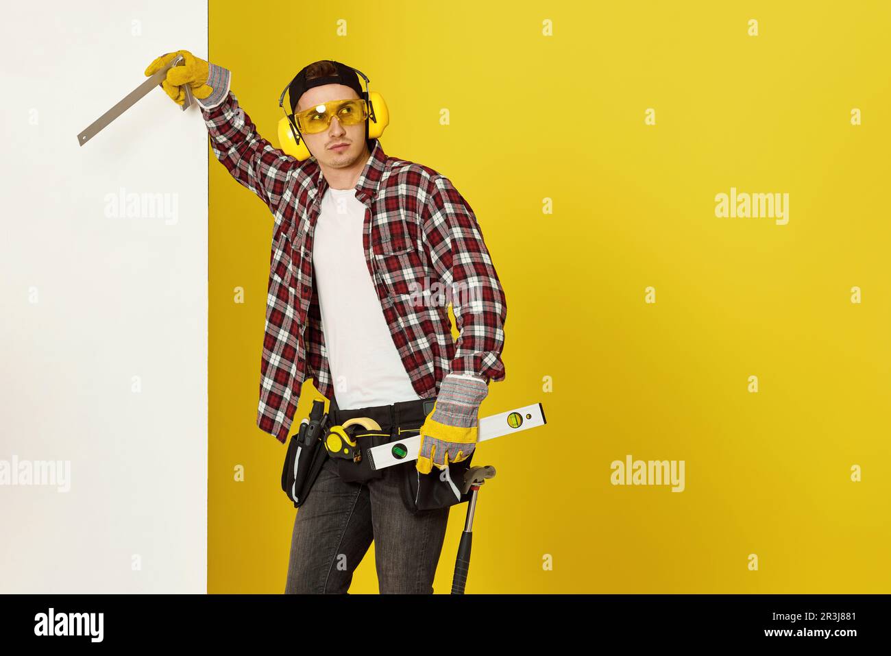 Worker man or builder in construction helmet near white banner on yellow background. building carpentry profession Stock Photo