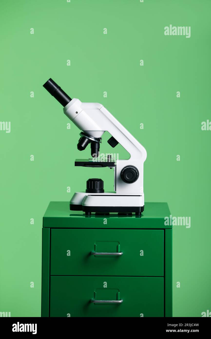 Modern medical microscope on lab drawer against green background Stock ...