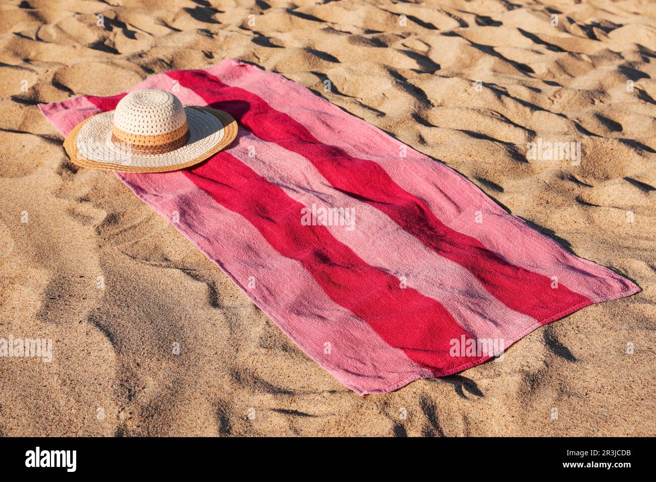 Beach towel and straw hat on sand Stock Photo - Alamy