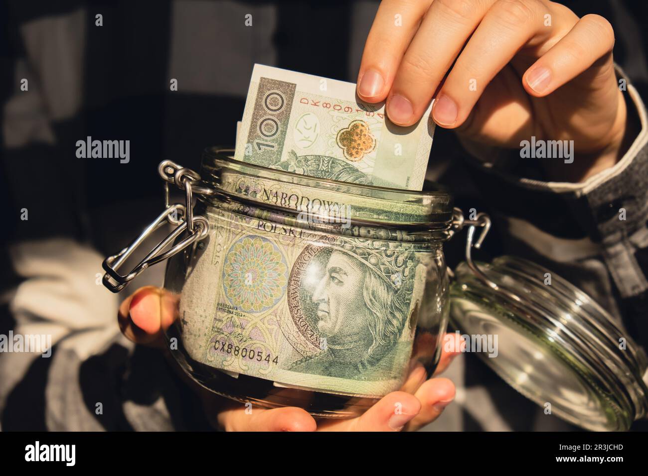 Polish zloty banknote saving money in glass jar. Unrecognizable woman moderate consumption and economy Collecting money. Tips. B Stock Photo