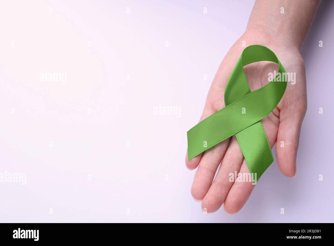 World Mental Health Day. Woman holding green ribbon on white background ...