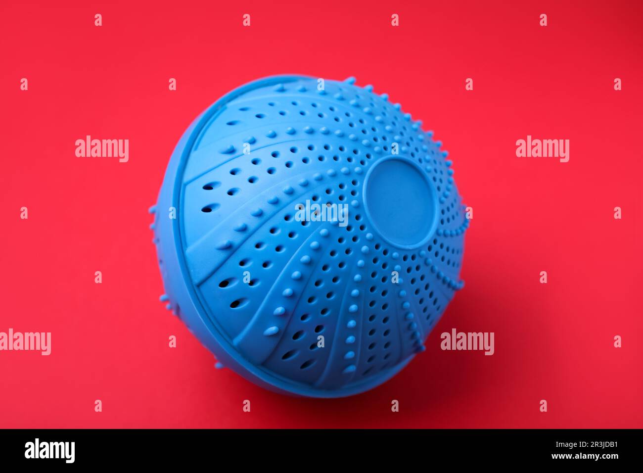 Dryer ball for washing machine on red background. Laundry detergent