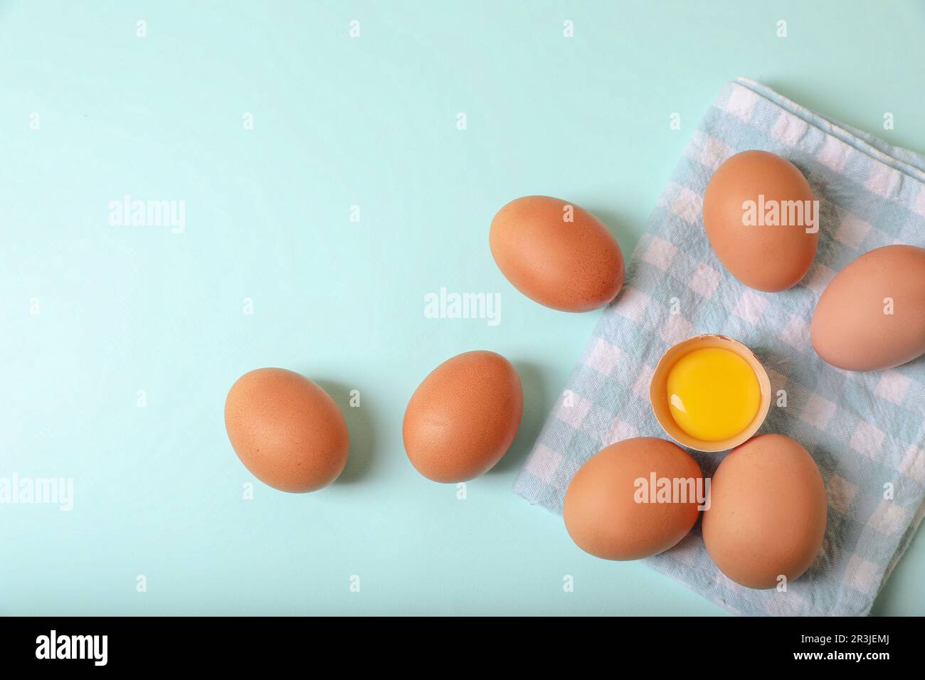 Cracked and whole chicken eggs with napkin on light blue background ...