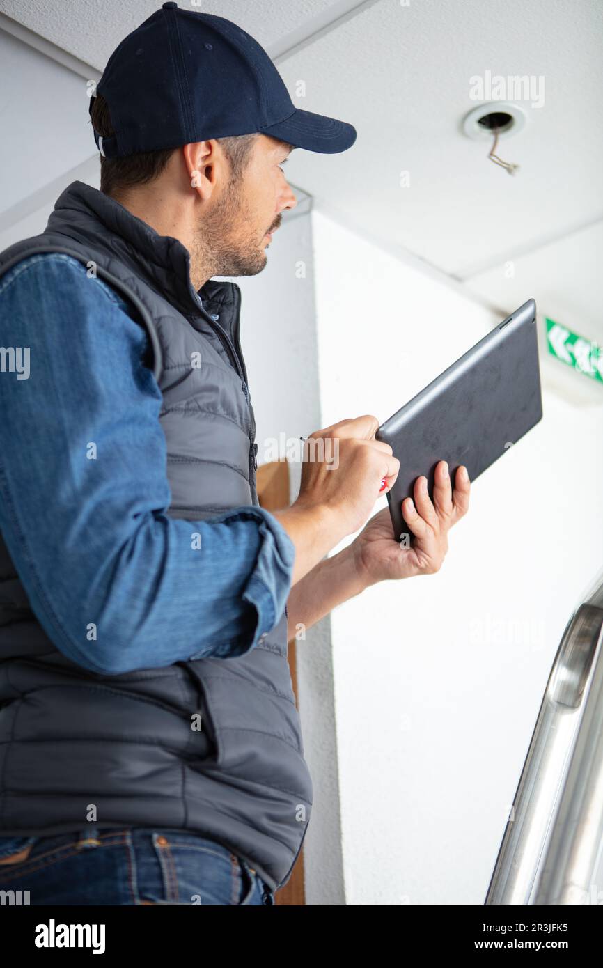 electrician repairing ceiling light at site Stock Photo