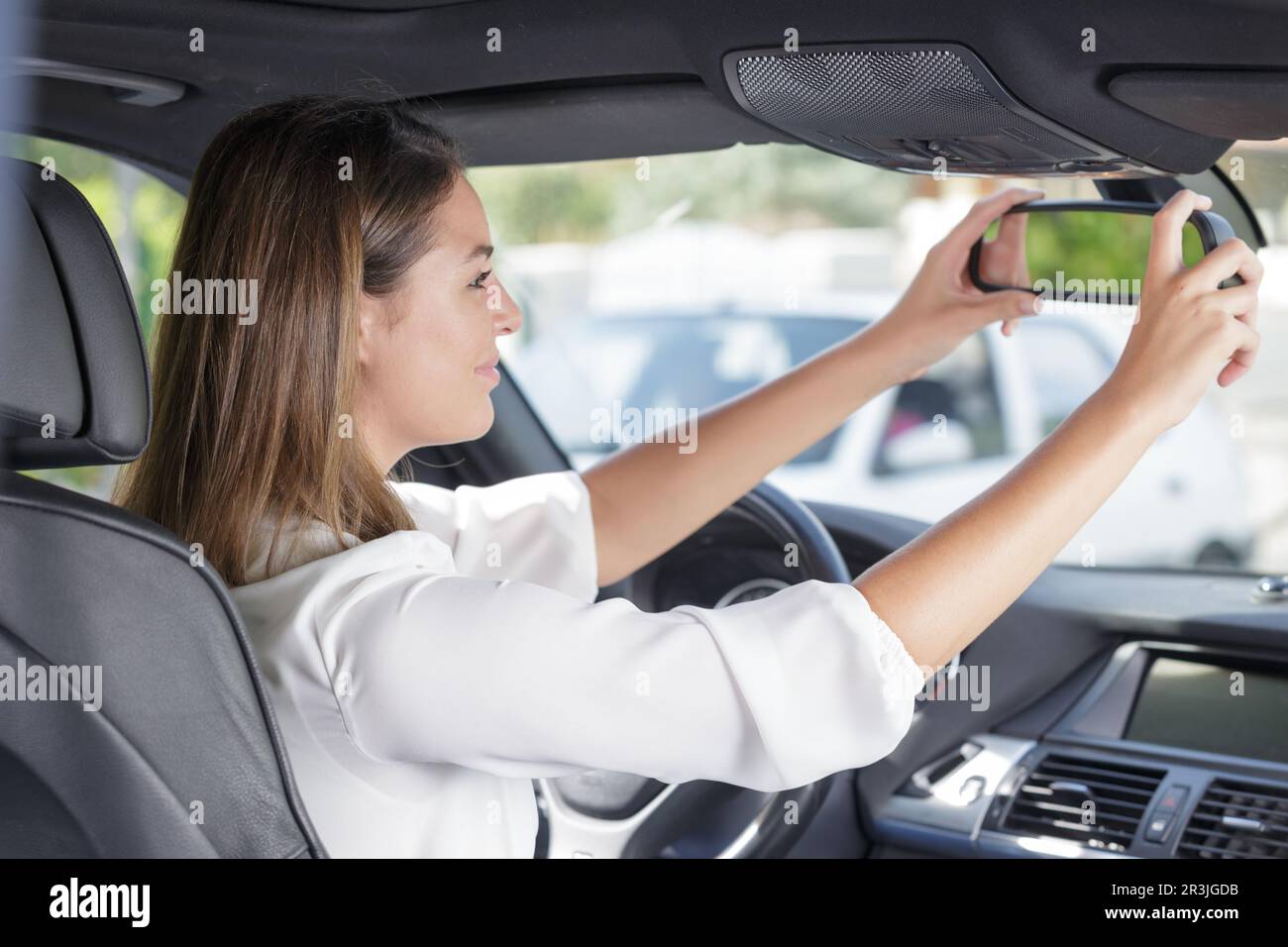 gorgeous brunette fixing up rearview car mirror Stock Photo