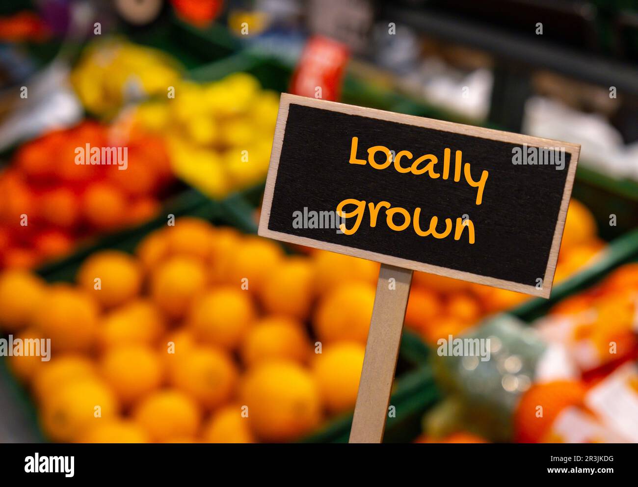 Wooden information label sign with text LOCALLY GROWN against defocused store shelves message. supporting local farmers Harvest Stock Photo