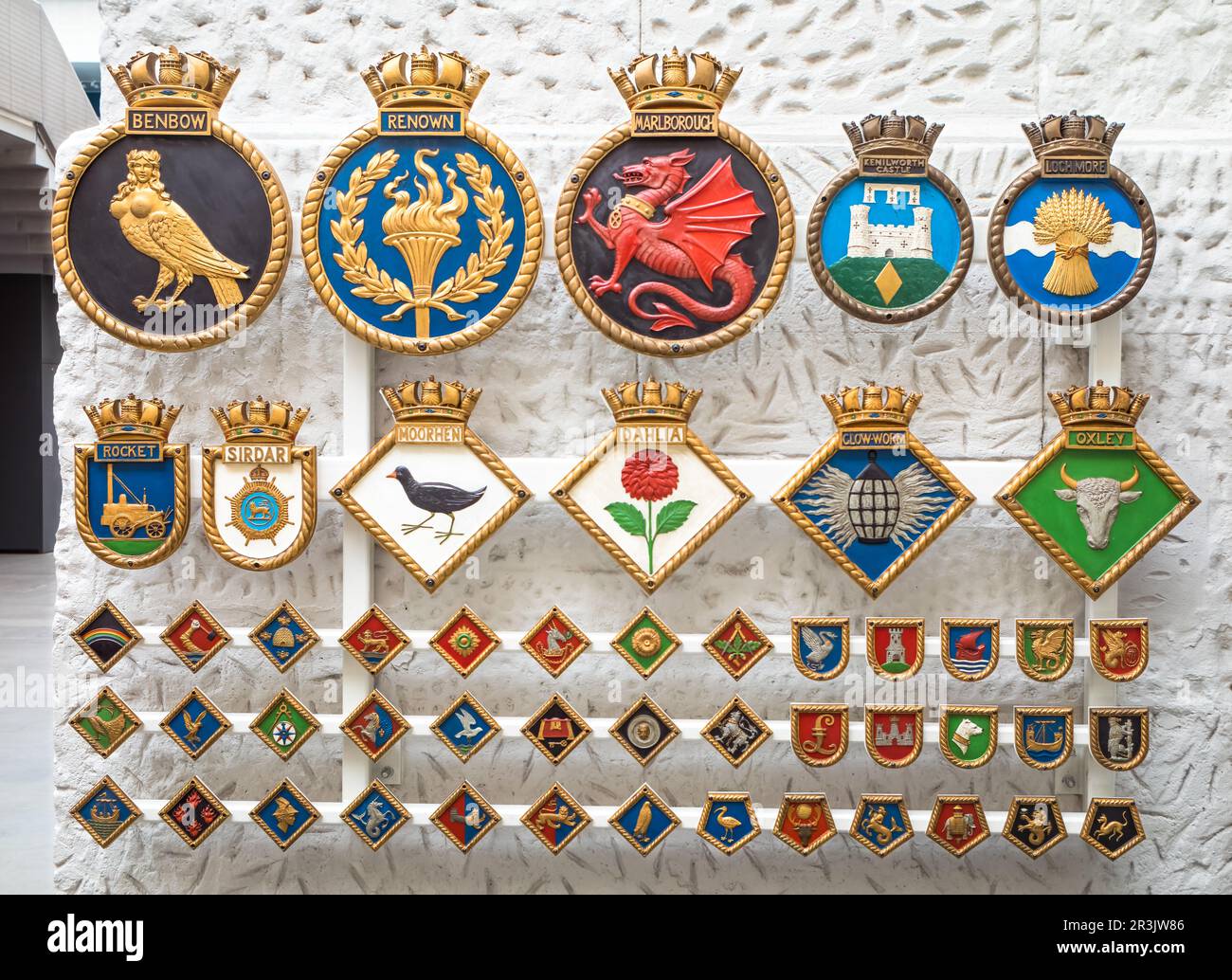 A display of Royal Navy ship's badges in the National Maritime Museum, in Greenwich, London, UK. The intricate designs with vibrant colours are proud Stock Photo