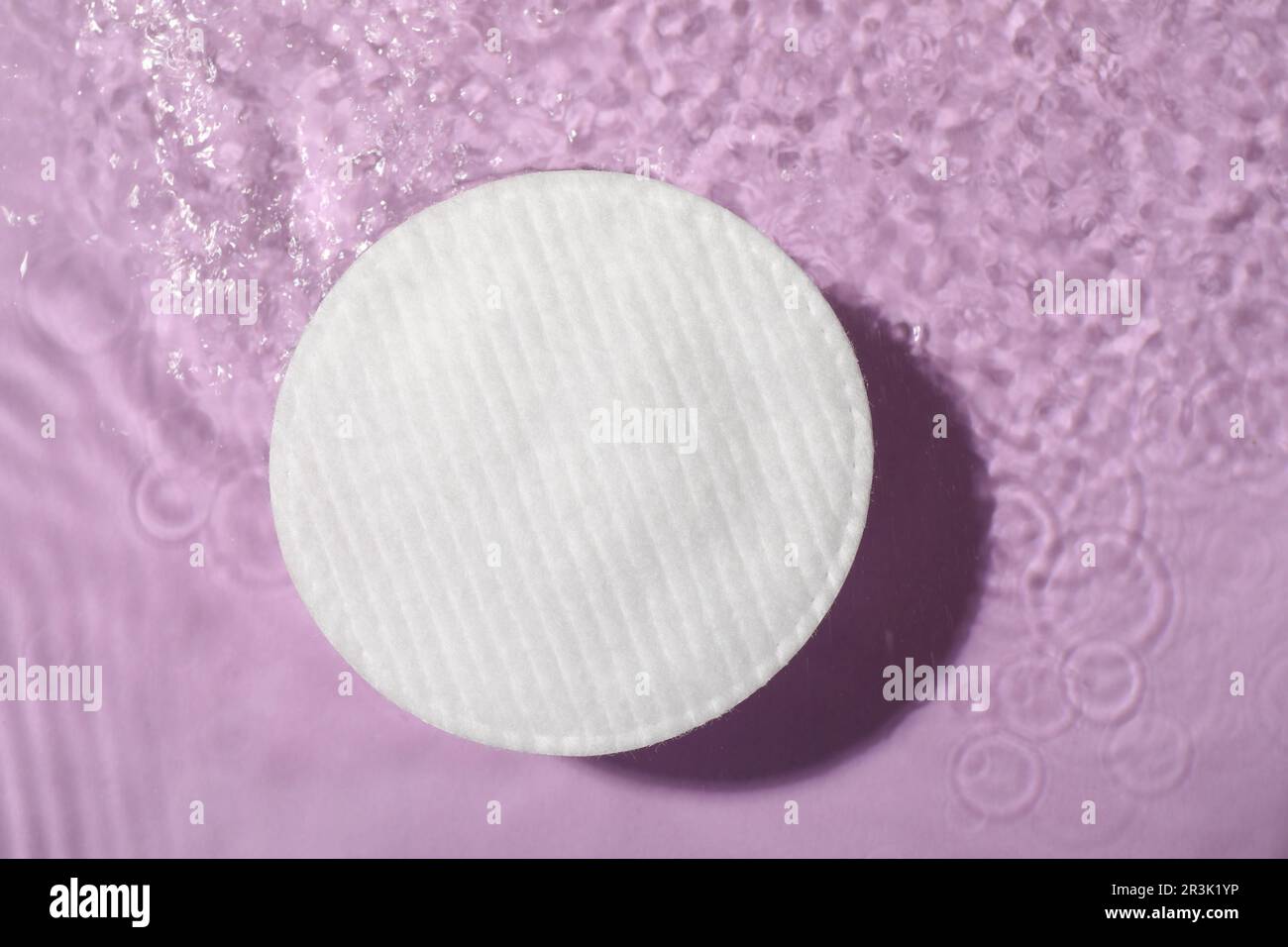 Cotton pad and micellar water on violet background, top view Stock Photo