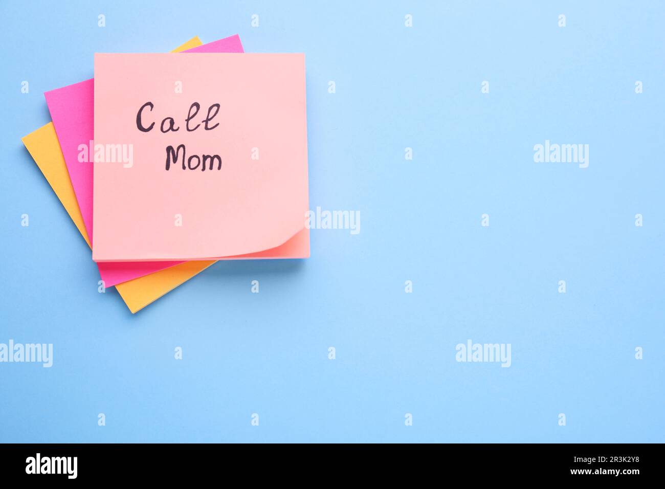 Paper note with phrase Call mom on light blue background, top view ...