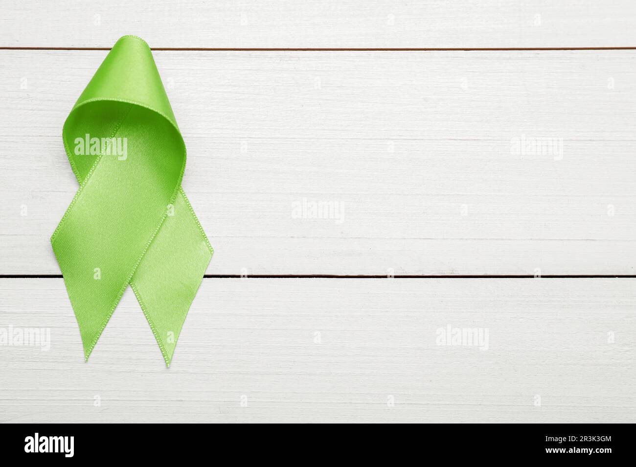 World Mental Health Day. Green ribbon on white wooden background, top ...
