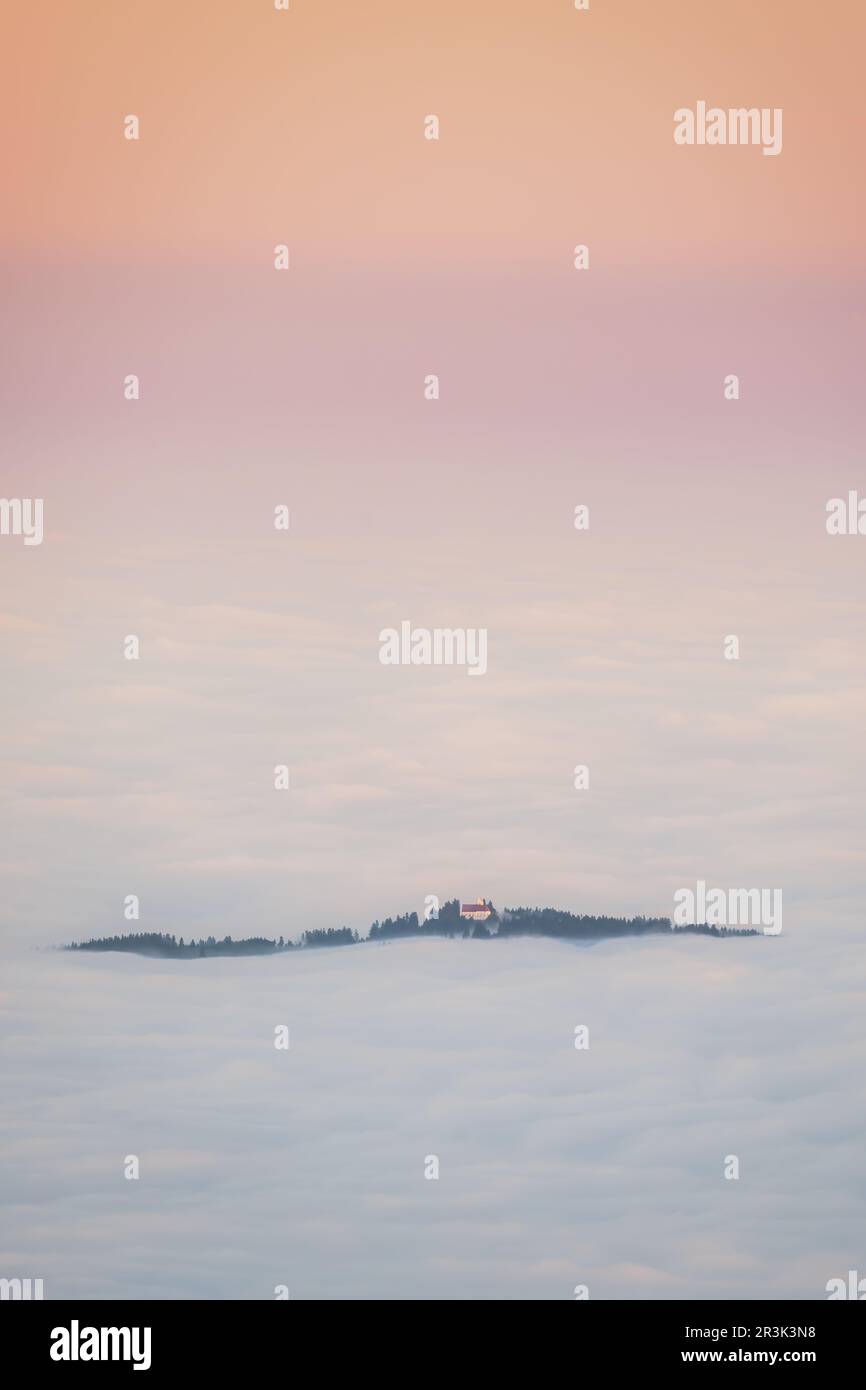 Curch peaking outside the clouds at sunrise, Bavaria, Alps, FÃ¼ssen, Ammergauer Alpen Stock Photo