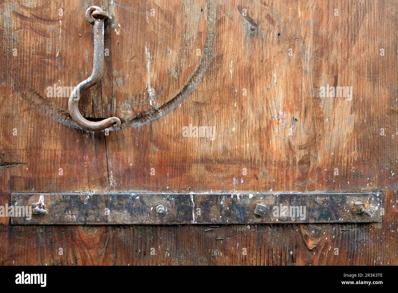 Fragment of an old wooden gate painted brown with a rusty metal plank and a locking hook close up view Stock Photo